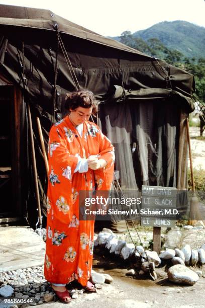 Outside her tent, Lieutenant Slack of the 8063rd MASH adjust the sleeve of her brightly colored kimono, South Korea, January 1952.