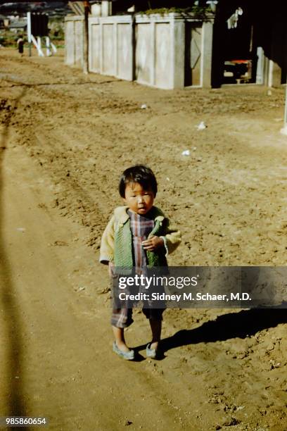 Portrait of a young girl as she stands on a dirt road, Inchon, South Korea, January 1952.