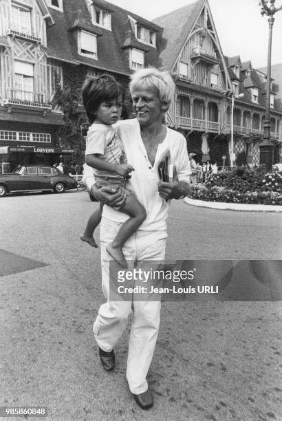 Klaus Kinski portant son fils Nikolai dans ses bras le 8 septembre 1979 dans une rue de Deauville, France.