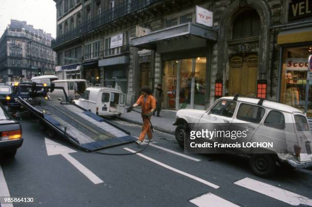 Un employé de la fourrière enlève une voiture dans une rue de Paris en mai 1985, France.