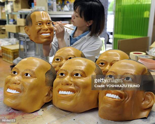 An employee of Japanese toy mask maker Ogawa Rubber, paints eyes on a rubber mask resembling US top golfer Tiger Woods at the company's factory in...