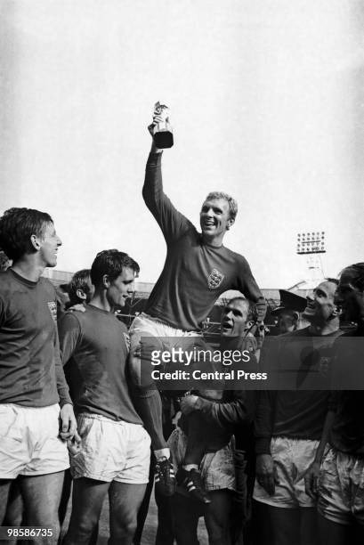 England captain Bobby Moore holds aloft the Jules Rimet World Cup trophy as he sits on the shoulders of teammates Geoff Hurst and Ray Wilson after...