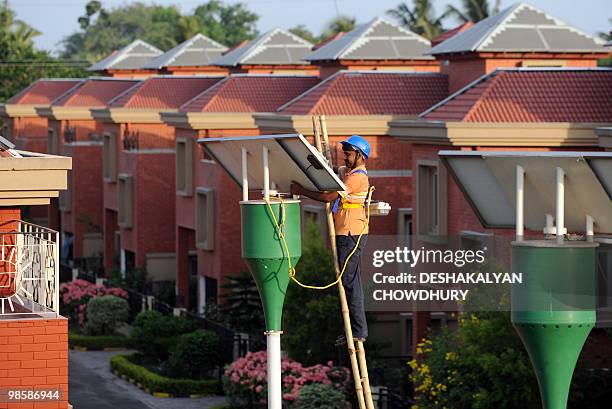 An Indian worker cleans a solar panel at Rabirashmi Abasan, a solar housing complex at Rajarhat close to Kolkata, on April 20, 2010. Consisting of 25...
