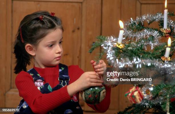 Petite fille décorant un sapin de Noël, France.