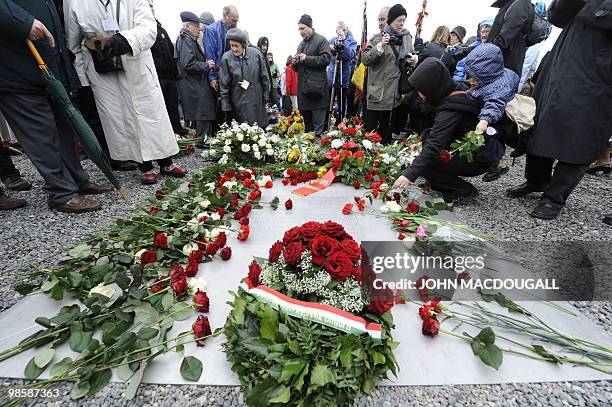 Woman carrying her baby lays a flower on a memorial plaque during celebrations marking the 65th anniversary of the liberation of the Buchenwald Nazi...