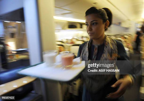 An air hostess attends passengers of a London-bound state-run Pakistan International Airlines flight inside the plane prior to take off from Karachi...