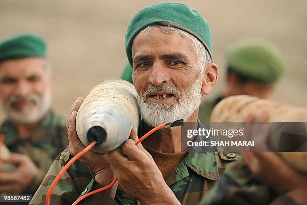 Afghan National Army soldiers carry shells to be used as explosives to destroy a cache of ammonium nitrate fertilizer in a controlled explosion on a...