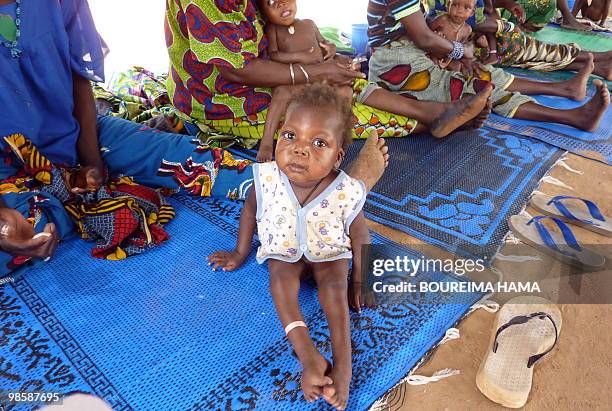 An infant suffering from malnutrition and malaria sits with others as they wait for treatment at a French NGO MSF outpost in Guidan-Roumdji. After...