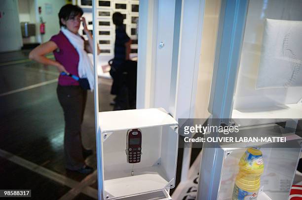 Woman stands behind counterfeit items seized by French customs and shown on April 21, 2010 during an exhibition on counterfeiting at the Cite des...