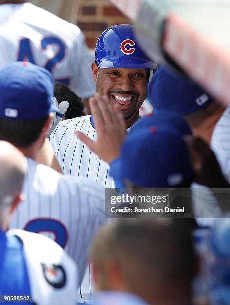 Derrek Lee of the Chicago Cubs, wearing a number 42 jersey in honor of Jackie Robinson, is greeted by teammates in the dugout after hitting a home...