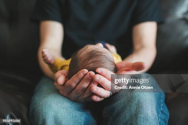 fathers hands holding newborn - vida de bebé fotografías e imágenes de stock