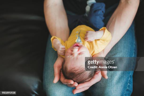 Fathers hands holding yawning newborn