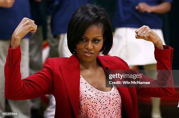 First lady Michelle Obama flexes her muscles as she exercises with schoolchildren at the River Terrace School April 21, 2010 in Washington, DC. Mrs....