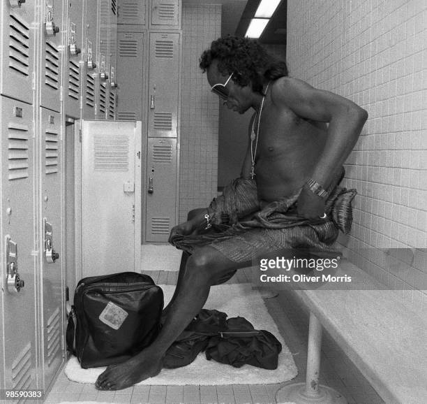 American jazz musician Miles Davis sits on a bench in the locker room of the health club atop the UN Plaza Hotel, New York, New York, mid 1980s.