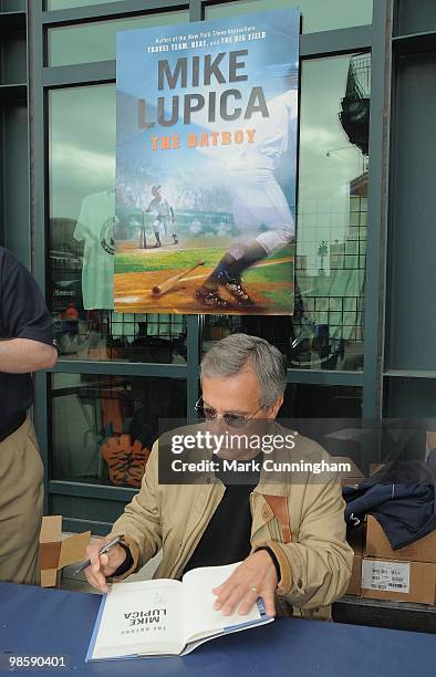 Author Mike Lupica signs a copy of his new book "The Batboy" before the baseball game between the Detroit Tigers and the Cleveland Indians at...