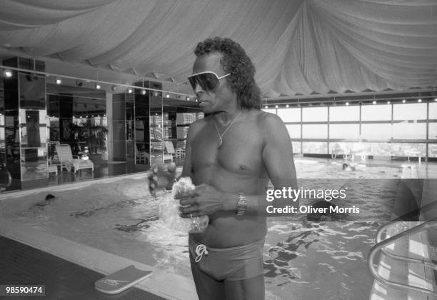 American jazz musician Miles Davis , in his sunglasses and swim trunks, and dons a hairnet on the deck of the swimming pool at the health club atop...