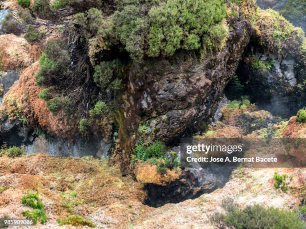 volcanic fumaroles with holes between the rocks issuing gases, surrounded with mosses and plants. terceira island in the azores islands, portugal. - stratovolcano 個照片及圖片檔