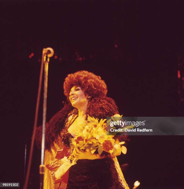Welsh singer Shirley Bassey performs live on stage holding a bouquet of flowers in 1978.