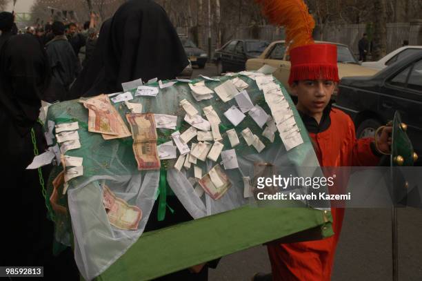 Young boy dressed as a warrior accompanies a group of women dressed in black chador in re-enactment act of The Day of Ashura which is on the 10th day...