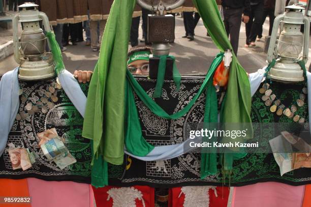 Boy holding wears a green headband, during a procession, in re-enactment act of The Day of Ashura. Ashura Day is on the 10th day of Muharram in the...