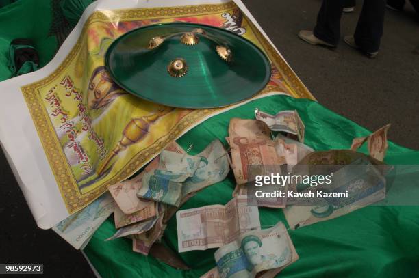 Islamic Republic banknotes with picture of Ayatollah Khomeini on them, are pinned on a dummy coffin carried by mourners with a shield placed on a...