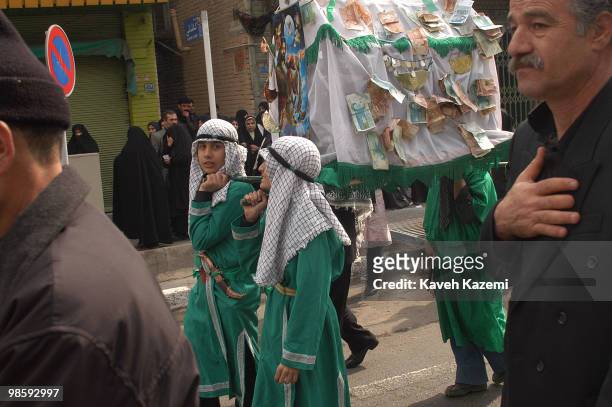 Young boys dressed in green, carry a makeshift tent, with a poster of Battle of Karbala pinned on, showing Imam Hussein, during a re-enactment act of...