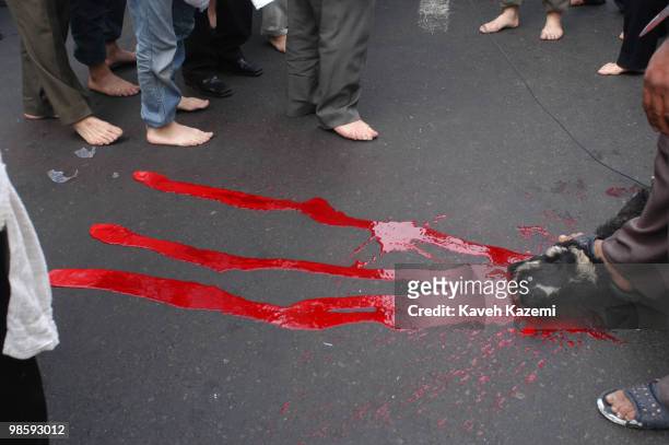 Barefeet men stand around while blood of a sacrificed lamb flows on the asphalt outside a mosque, in south Tehran, on The Day of Ashura in south...