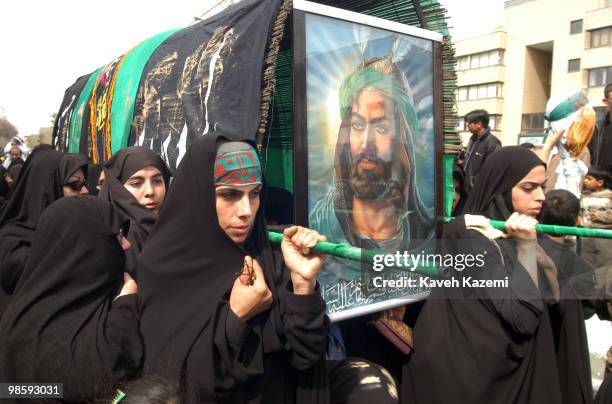 Group of women dressed in black chador carry a dummy coffin with poster of Imam on it, in south Tehran on The Day of Ashura which is on the 10th day...