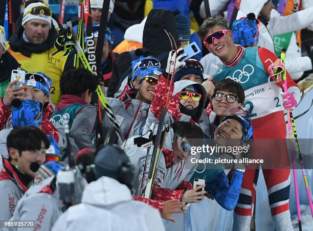 Norway's Johannes Hoesflot Klaebo takes pictures with his fans after coming in first at the men's cross-country skiing classic sprint at the Alpensia...