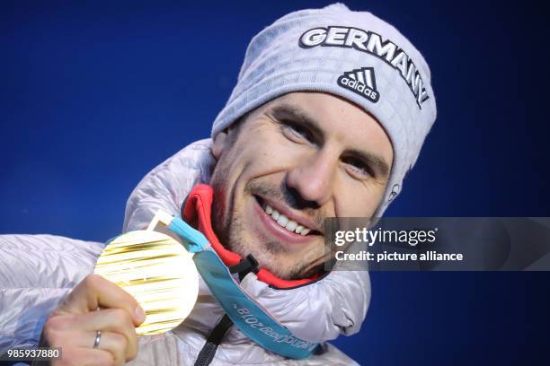 Dpatop - German gold medallist Arnd Peiffer celebrates on the podium during the medal ceremony of the men's 10km biathlon sprint on day four of the...