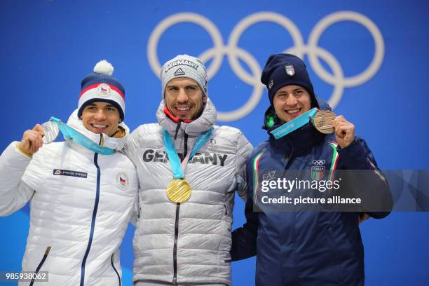 Dpatop - Czech silver medallist Michal Krcmar , German gold medallist Arnd Peiffer and Italian bronze medallist Dominik Windisch celebrate on the...