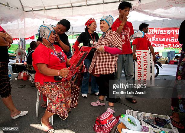 Anti -Government Red Shirt supporters of ousted premier Thaksin Shinawatra color their hair at a makeshift hair saloon in the Red compound, as the...