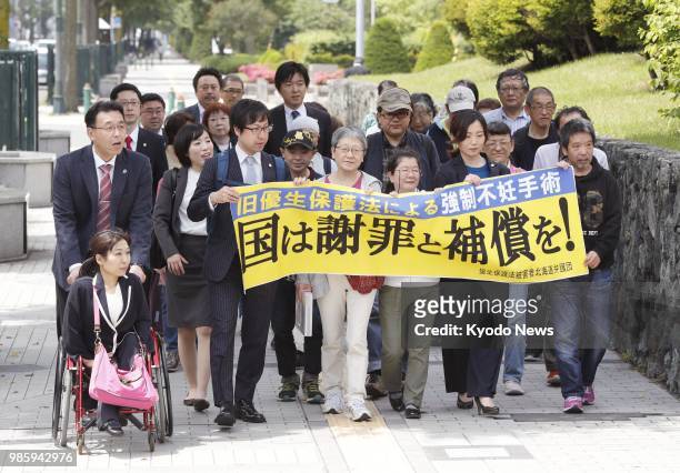 Supporters of a Japanese married couple seeking damages from the government march to the Sapporo District Court in Hokkaido on June 28 to file a...