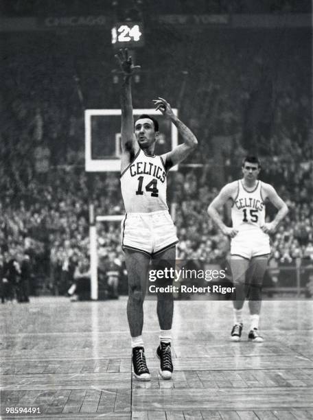 Bob Cousy of the Boston Celtics shoots a free throw against the Cincinnati Royals as Tom Heinsohn looks on during a game in the 1962-63 season at...