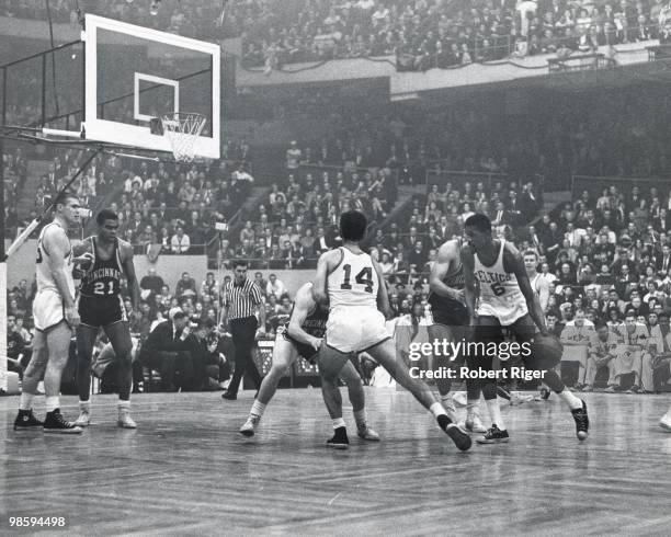 Bill Russell of the Boston Celtics dribbles as Bob Cousy sets a screen and Tom Hawkins of the Cincinnati Royals guards Tom Heinsohn during a game in...