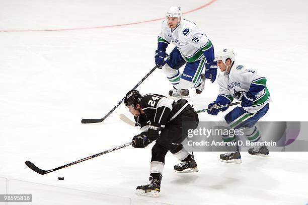 Alexander Frolov of the Los Angeles Kings skates with the puck against Kevin Bieksa and Aaron Rome of the Vancouver Canucks in Game Three of the...