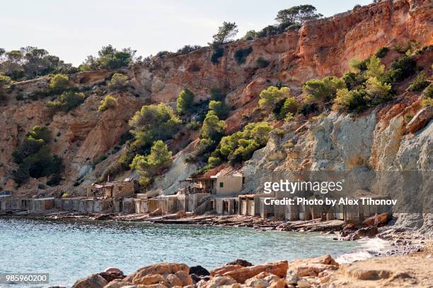 cala d'hort beach and boat garages. ibiza island. spain - beach at cala d'or stock pictures, royalty-free photos & images