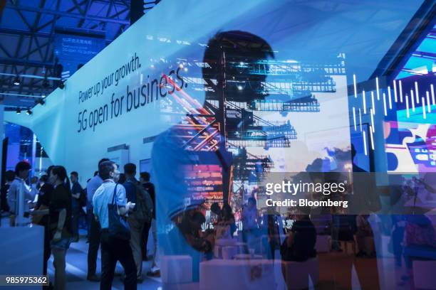 Projected image of gantry cranes is reflected on a pane of glass at the Ericsson AB booth at the Mobile World Congress Shanghai in Shanghai, China,...
