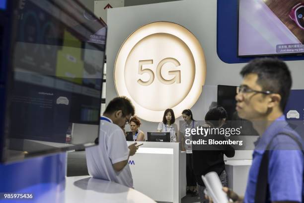 Attendees walk past signage for 5G at the Qualcomm Inc. Booth at the Mobile World Congress Shanghai in Shanghai, China, on Thursday, June 28, 2018....