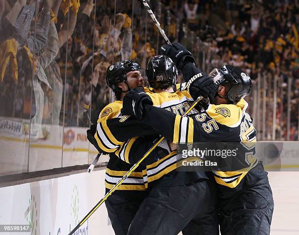 Miroslav Satan of the Boston Bruins is swarmed by teammates Dennis Wideman and Johnny Boychuk after Satan scored the game winnner against the Buffalo...