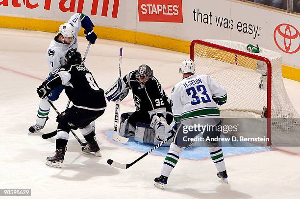 Jonathan Quick of the Los Angeles Kings looks for the puck as teammate Drew Doughty plays defense against Ryan Kesler and Henrik Sedin of the...