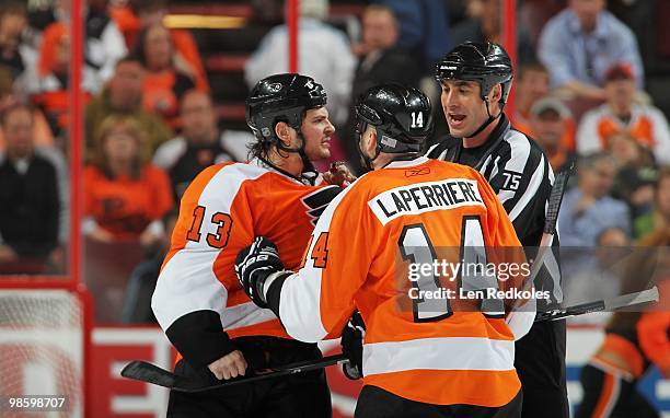 Dan Carcillo of the Philadelphia Flyers is restrained by teammate Ian Laperriere and Linesmen Derek Amell during a scrum against the New Jersey...