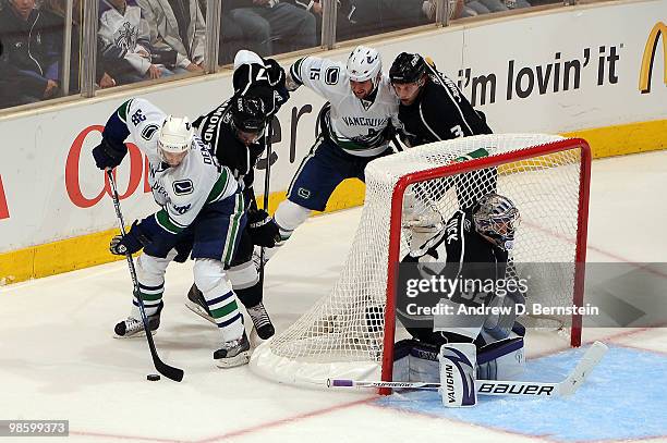 Pavol Demitra of the Vancouver Canucks skates with the puck against Wayne Simmonds and Jonathan Quick of the Los Angeles Kings while Tanner Glass of...