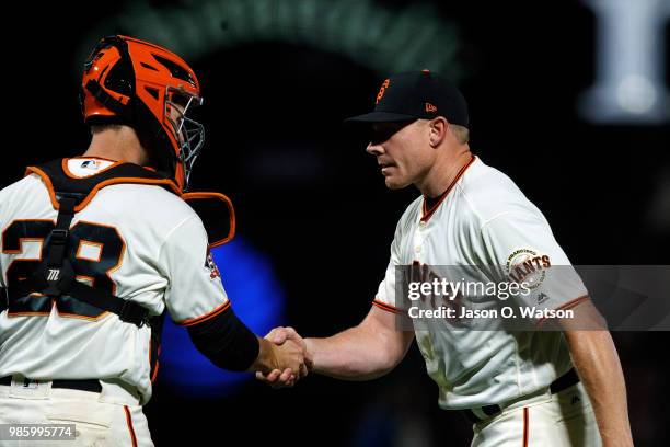 Mark Melancon of the San Francisco Giants celebrates with Buster Posey after the game against the San Diego Padres at AT&T Park on June 21, 2018 in...