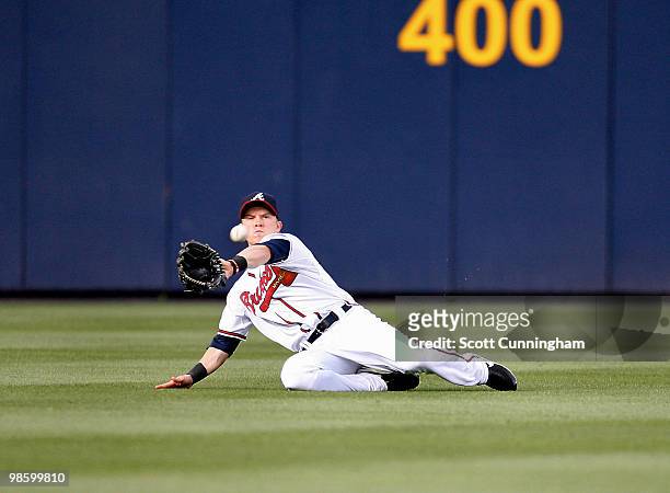 Nate McLouth of the Atlanta Braves makes a sliding catch against the Philadelphia Phillies at Turner Field on April 21, 2010 in Atlanta, Georgia. The...