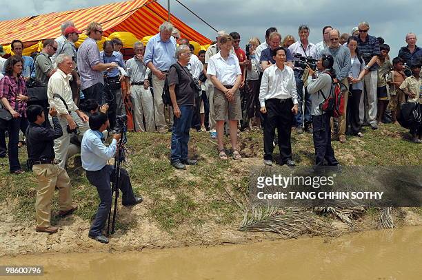 Current and former foreign correspondents observe a moments of silence in front of a grave at a rice field in Kampong Speu province, some 70...