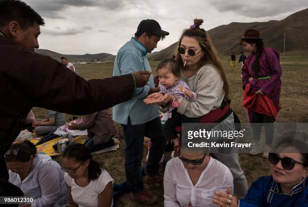 Mongolian followers of Shamanism or Buu murgul, takes rice as a blessing during a ceremony in the grasslands on June 21, 2018 outside Ulaanbaatar,...