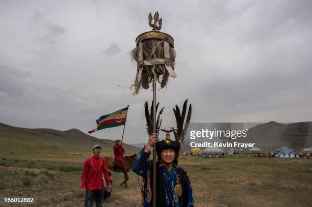 Mongolian Shaman or Buu, carries a banner from the period of Chinggis Khan before a fire ritual meant to summon spirits to mark the period of the...