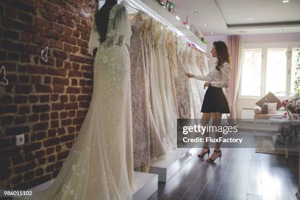 vrouw oppakken van een perfecte trouwjurk - bridal shop stockfoto's en -beelden