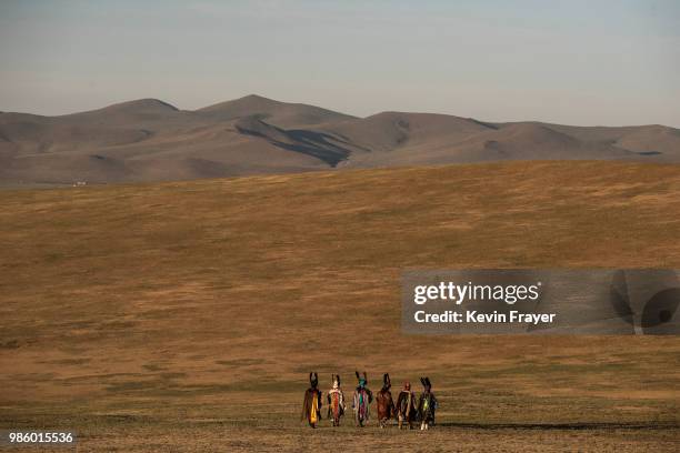 Mongolian Shamans or Buu, walk away following a sun ritual ceremony to mark the period of the Summer Solstice in the grasslands at sunrise on June...